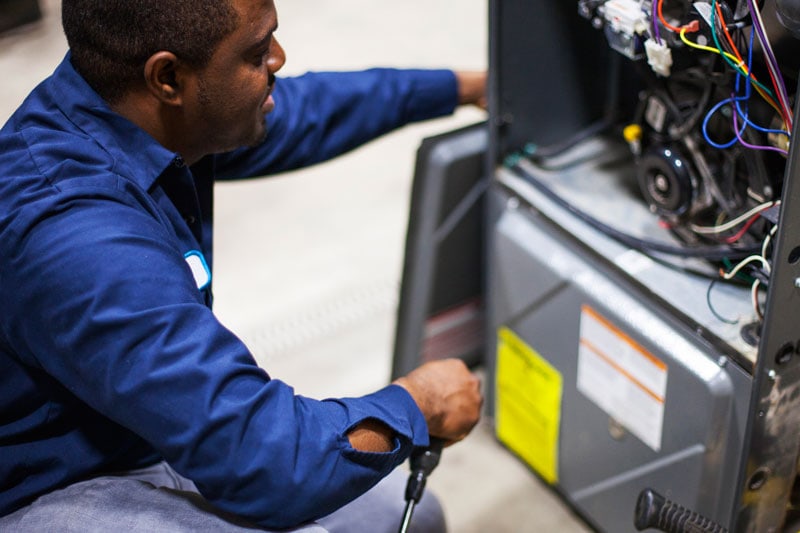 prosolutions furnace technician inspecting a high efficiency furnace during annual maintenance.